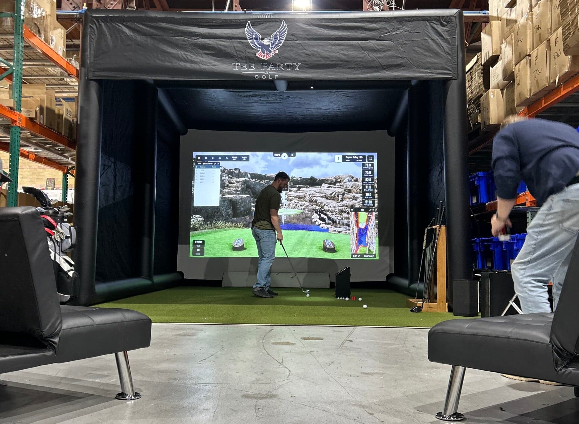 A full Tee Party Golf simulator enclosure with guest seating